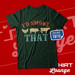 May include: Green t-shirt with the text "I'd Smoke That" in red, white, and blue. The text is surrounded by images of a chicken, pig, and cow. The shirt also has a small white label with the text "Ships Today (or next business day) 18 Colors S-4XL".
