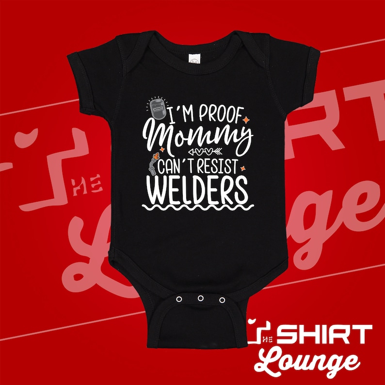 May include: Black baby onesie with white text that reads "I'm proof mommy can't resist welders". The text is surrounded by small hearts and stars.