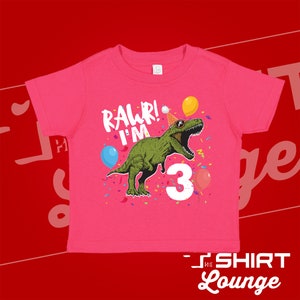 May include: Pink t-shirt with a green dinosaur wearing a party hat and sunglasses. The dinosaur is saying "Rawr! I'm 3" with confetti and balloons around it.