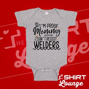 May include: Gray baby onesie with a black graphic that reads "I'm proof mommy can't resist welders". The graphic includes a welding mask, a welding torch, and hearts.