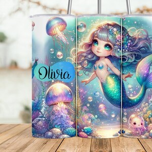 May include: A personalized tumbler with a mermaid illustration. The mermaid has long blue hair, a green tail, and is surrounded by jellyfish and bubbles. The tumbler is white with the name "Olivia" written on it.