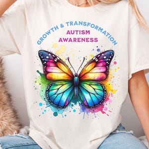 May include: A white t-shirt with a colorful butterfly graphic and the text "Growth & Transformation Autism Awareness".