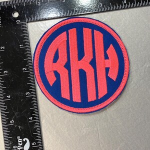 May include: A pink and blue embroidered patch with the letters "RKH" in a circle.