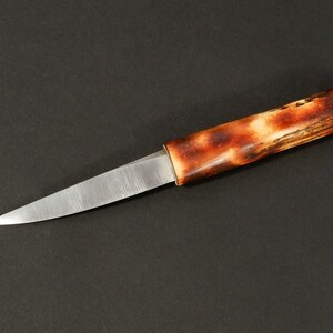 Może przedstawiać: Mały, srebrny nóż z brązową, drewnianą rękojeścią. Ostrze jest ostre, a rękojeść gładka.