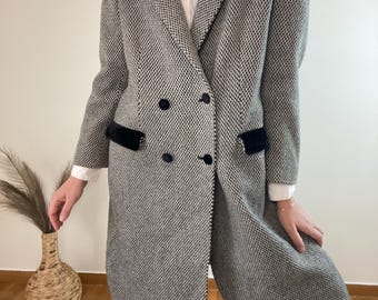 Pode incluir: Um casaco de abotoamento duplo com padrão preto e branco com detalhes de gola e bolsos em veludo preto. O casaco tem botões pretos e um corte longo e sob medida. Parte de uma coleção de roupas vintage.