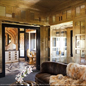 May include: A gold-toned room with mirrored cabinets and a large leather couch with a fur throw. The room has a luxurious and elegant feel.