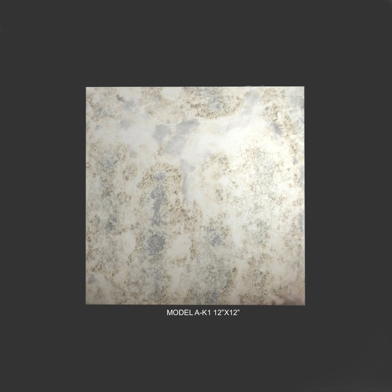 May include: A close-up of a distressed, antique-looking mirror tile. The tile has a white background with brown and grey markings. The tile is 12 inches by 12 inches. The text "MODEL A-K1 12"X12"" is printed below the tile.