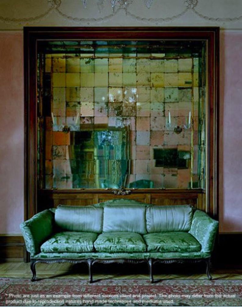 Puede incluir: Un sof&aacute; de terciopelo verde con marco de madera se encuentra frente a una pared con un gran espejo antiguo hecho de muchas peque&ntilde;as piezas cuadradas de vidrio.