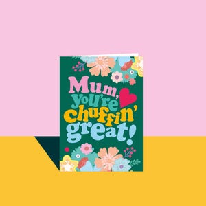 May include: A greeting card with the text "Mum, you're chuffin' great!" in colorful, retro-style lettering. The card is decorated with floral illustrations in shades of pink, peach, blue, and yellow against a dark green background.