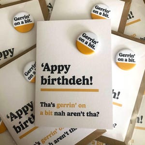 May include: Greeting cards with the text "'Appy birthdeh!" and "Tha's gerrin' on a bit nah aren't tha?" are displayed. Each card is accompanied by a white and yellow button that reads "Gerrin' on a bit."