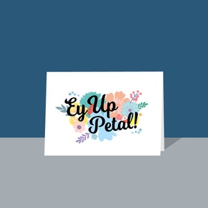 May include: A white card with a floral design and the text "Ey Up Petal!" in black cursive font.