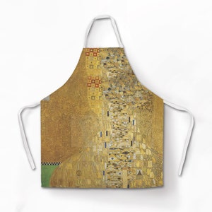 May include: A white apron with a gold and green abstract design. The design is reminiscent of a famous painting.