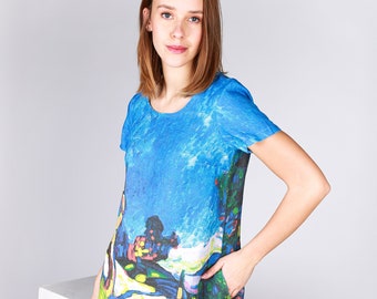 May include: A short-sleeved shift dress featuring a vibrant, multi-colored landscape print with dominant shades of blue, green, yellow, and black. The dress has a round neckline, a straight silhouette, and includes functional side pockets.