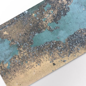 Può includere: Primo piano di una superficie testurizzata con vernice blu-verde sbiadita e sfondo dorato. La superficie ha una consistenza ruvida e irregolare con aree di vernice che si stacca e oro esposto.