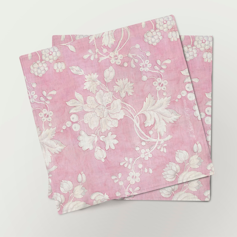 May include: Two pink fabric napkins with a white floral pattern. The napkins are folded and stacked on top of each other.