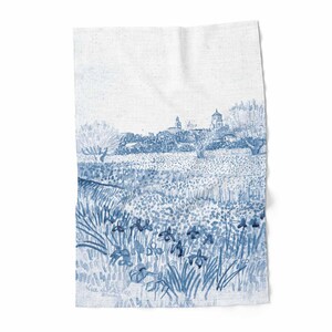 Könnte beinhalten: Ein weißes Leinentuch mit einer blauen Aquarellillustration einer Landschaft. Das Design zeigt ein Blumenfeld, Bäume und ein entferntes Dorf mit Gebäuden und einer Kirche. Das Kunstwerk erinnert an ein klassisches Gemälde.