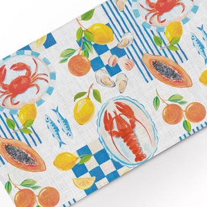 Peut inclure: Un chemin de table en lin blanc avec un motif à carreaux bleu et blanc. Le chemin de table présente un motif répétitif de citrons, d'oranges, de papayes, d'huîtres, de poissons, de homards et de crabes. Le design est peint dans un style aquarelle.