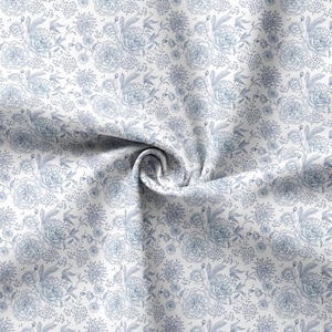 May include: White fabric with a blue floral pattern. The fabric is folded and twisted, showing the pattern in detail.