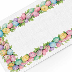 以下が含まれることがあります： 水彩デザインの白いイースターテーブルランナー。縁には、ピンク、青、黄色、紫の色合いのカラフルなイースターエッグが、緑の葉でアクセントされています。ウサギや花の模様が入った卵もあります。