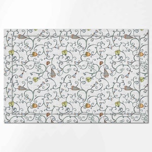 Puede incluir: Un mantel individual blanco con un patr&oacute;n repetitivo de dise&ntilde;os florales azules, verdes y naranjas sobre un fondo gris.