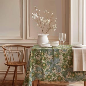Pode incluir: Uma mesa branca com uma toalha de mesa floral, duas taças de vinho e um jarro branco com flores brancas. A mesa está posta com tigelas brancas e um guardanapo branco.