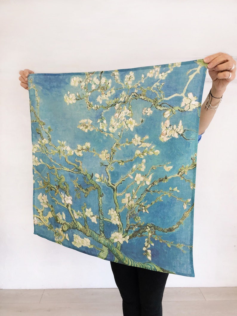 K&ouml;nnte beinhalten: Eine blaue und gr&uuml;ne Stoffwandteppich mit einem Gem&auml;lde eines bl&uuml;henden Mandelbaums mit wei&szlig;en Bl&uuml;ten vor blauem Himmel.