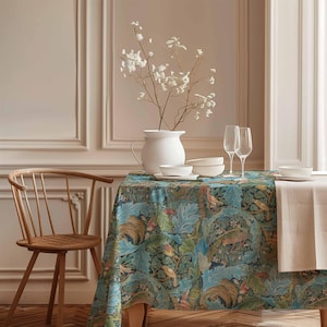 May include: A dining table set with a teal tablecloth featuring a botanical pattern. The table is set with white dishes, wine glasses, and a white vase with white flowers. A wooden chair is on the left.