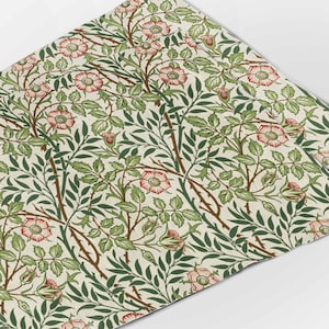 May include: A repeating pattern of pink and green floral designs on a cream background. The pattern features stylized roses, leaves, and stems.