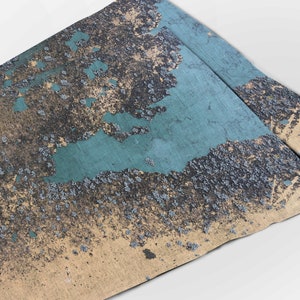 May include: A close-up of a textured surface with a teal blue paint that is peeling and flaking off. The surface is covered in small black and gray specks.