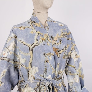 Peut inclure: Une robe bleu clair avec un imprimé floral d'un arbre avec des fleurs blanches. La robe a une ceinture à nouer et des manches longues.