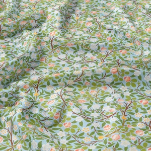 May include: A blue fabric with a repeating pattern of white flowers and orange-red blossoms on leafy branches.
