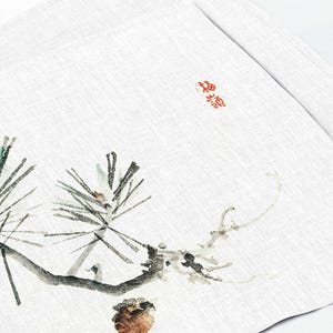 May include: A black and white ink painting of a pine branch with two pine cones. The painting is on a white background with a red stamp in the upper right corner that says "福".