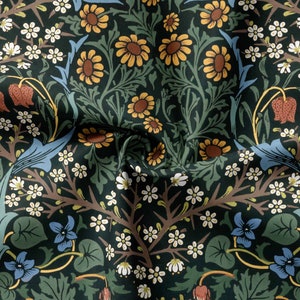 Op de afbeelding: Een donkergroene stof met een herhalend bloemenpatroon. Het patroon bevat blauwe, witte, gele en rode bloemen. De stof is textuurrijk en heeft een vintage uitstraling.