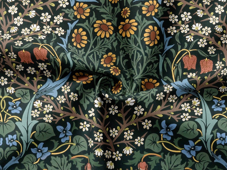 Op de afbeelding: Een donkergroene stof met een herhalend bloemenpatroon. Het patroon bevat blauwe, witte, gele en rode bloemen. De stof is textuurrijk en heeft een vintage uitstraling.