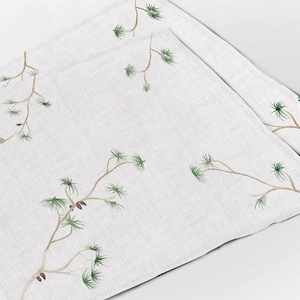 Peut inclure: Ensemble de deux sets de table en lin blanc avec un motif répété de branches de pin vertes et de pommes de pin brunes.
