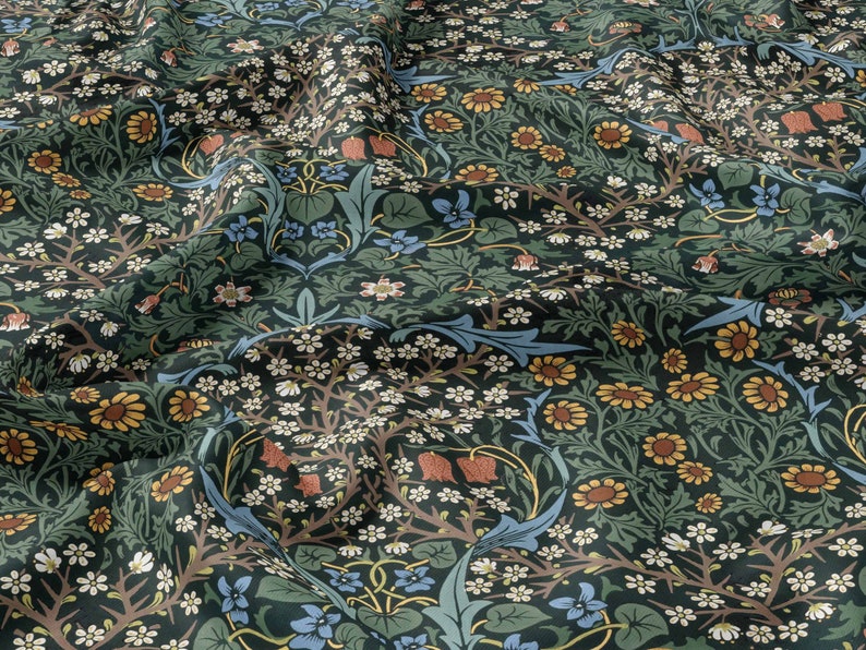 Op de afbeelding: Een groene stof met een herhalend bloemenpatroon. Het patroon bevat kleine witte bloemen, gele bloemen, blauwe bloemen en rode bloemen. De stof heeft een textuur.