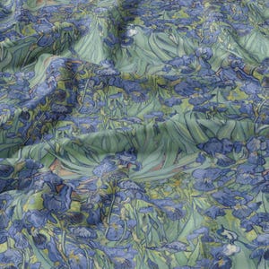 May include: A fabric featuring a repeating pattern of blue irises and green foliage, resembling a painting. The fabric has a soft, flowing appearance, with visible folds and creases. The design features a variety of blue hues, with accents of green and yellow.