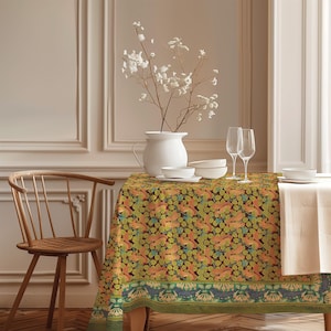 Puede incluir: Un mantel rectangular con un patrón repetitivo de ardillas naranjas, hojas verdes y pequeñas flores azules sobre un fondo oscuro, con un borde decorativo en la parte inferior. La tela está colocada sobre una mesa con cuencos de cerámica blanca.