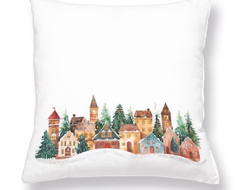May include: White square pillow featuring a watercolor illustration of a winter village scene. The design includes colorful houses, evergreen trees, and a snowy landscape. The pillow is a decorative item.