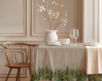May include: A beige rectangular tablecloth featuring a printed border of green pine trees along the bottom edge. The table is set with a white ceramic pitcher containing white flowers, white bowls, and two clear glass flutes on stems.