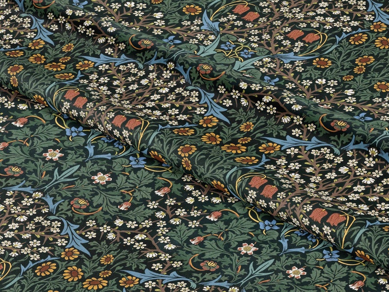 Op de afbeelding: Een donkergroene stof met een herhalend bloemenpatroon. Het patroon bevat kleine witte bloemen, gele en oranje bloemen, blauwe bloemen en rode bloemen. De stof heeft een textuur.