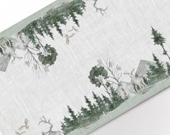 May include: A green and white table runner with a watercolor design of a forest scene. The design features trees, deer, and birds. The runner has a light green border.