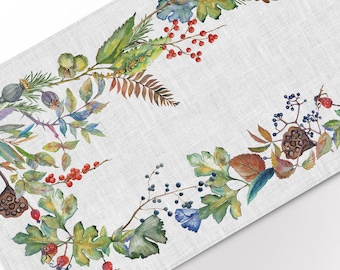 May include: A watercolor illustration of a floral garland with leaves, berries, and flowers in shades of green, blue, red, and brown. The garland is on a white linen background.