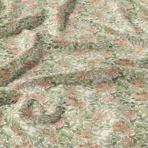 Könnte beinhalten: Ein weißer Stoff mit einem sich wiederholenden Muster aus orangefarbenen Blüten und grünen Blättern. Der Stoff ist zerknittert und hat eine weiche, natürliche Textur.