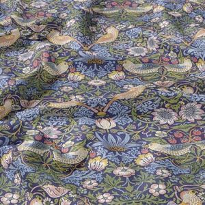 Pode incluir: Tecido azul marinho com um padrão repetido de pássaros, flores e folhagens em tons de bege, rosa e verde. O design evoca uma impressão botânica clássica, para decoração ou vestuário.