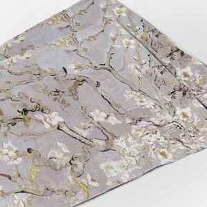 Pode incluir: Um conjunto de três placemats de linho cinza com um padrão floral branco e amarelo. O padrão é reminiscente de uma famosa pintura de uma amendoeira em flor.