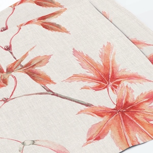 Peut inclure: Un tissu beige clair présentant un motif aquarelle répétitif de feuilles d'érable orange et rouge vif attachées à de fines branches brun foncé. Le textile possède une texture tissée visible et affiche un motif botanique sur la surface.