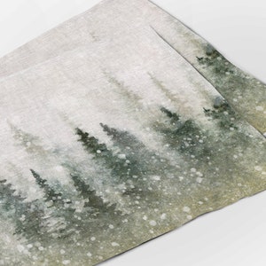 May include: A watercolor painting of a snowy forest scene with green trees and white snow falling. The background is a light gray color.
