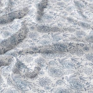 May include: White fabric with a blue floral pattern. The pattern features large peonies and smaller sprigs of flowers.