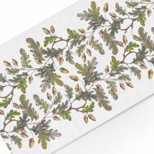 May include: A white linen table runner with a repeating pattern of brown acorns and green oak leaves.
